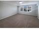 Spacious bedroom with neutral carpet and three bright windows, creating a versatile and inviting space at 6525 Dutton Dr, Wesley Chapel, FL 33545