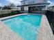 Inviting backyard pool with stone pavers, safety fence, and the home's rear exterior with covered patio at 6525 Dutton Dr, Wesley Chapel, FL 33545