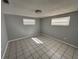 Neutral bedroom with tile floors, light walls, two windows, and a basic ceiling light at 5125 Janice Ln, Holiday, FL 34690