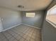 Small, simple bedroom with tile floors and neutral walls and two windows at 5125 Janice Ln, Holiday, FL 34690