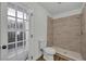 Modern bathroom featuring a tiled shower, toilet, wood-look floor and access door to the exterior at 4522 Marine Pkwy, New Port Richey, FL 34652