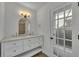 Bathroom vanity featuring double sinks, chrome faucets, arched mirror, and access door to the exterior at 4522 Marine Pkwy, New Port Richey, FL 34652
