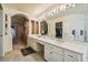 Luxurious bathroom with dual sinks, a large mirror with Hollywood lights and a walk-in closet at 26058 Paysandu Dr, Punta Gorda, FL 33983