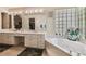 Bathroom featuring a large vanity with dual sinks, walk-in closet and a separate bathtub with privacy window at 26058 Paysandu Dr, Punta Gorda, FL 33983