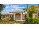 Charming one-story home featuring a manicured front yard, arched entryway, and lush tropical landscaping at 26058 Paysandu Dr, Punta Gorda, FL 33983
