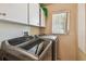 Bright laundry room with front-loading washer and dryer under bright cabinets at 26058 Paysandu Dr, Punta Gorda, FL 33983