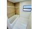 Clean bathroom featuring a white tub with tile surround and a bright window at 9151 Bay Dr, Spring Hill, FL 34606