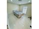 Well-lit bedroom boasts white tile, a gray bed with pillows, and a bright window with natural light at 9151 Bay Dr, Spring Hill, FL 34606