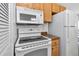 Bright kitchen featuring white appliances, wood cabinetry, and granite countertops for a modern feel at 6417 Driftwood Dr, Hudson, FL 34667