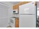 Compact kitchen featuring white appliances, wood cabinets and a neutral countertop at 6417 Driftwood Dr, Hudson, FL 34667