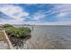 Beautiful waterfront view featuring lush green vegetation by the shore under a blue cloudy sky at 6417 Driftwood Dr, Hudson, FL 34667