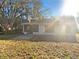 Home's backyard featuring a screened patio, a concrete pad, a grassy area, and mature trees at 8379 Begonia St, Spring Hill, FL 34608