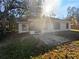 Rear view of home with a concrete patio surrounded by mature trees and lush greenery at 8379 Begonia St, Spring Hill, FL 34608