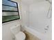 Bathroom with a shower-tub combo, a black-framed window, and a standard white toilet at 8379 Begonia St, Spring Hill, FL 34608