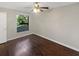 Bright bedroom with wood floors, neutral walls, a ceiling fan, and a window overlooking the backyard at 8379 Begonia St, Spring Hill, FL 34608