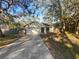 Home's exterior featuring a long driveway, an attached garage, neutral paint, and mature trees at 8379 Begonia St, Spring Hill, FL 34608