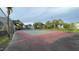 Community tennis court behind a chain link fence, with palm trees and mature trees around perimeter at 2850 Somerset Park Dr # 201, Tampa, FL 33613