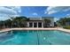 View of the community pool surrounded by lush landscaping and a building with stately white columns at 2856 Somerset Park Dr # 102, Tampa, FL 33613