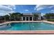 Community pool boasts clear blue water, surrounded by a red brick deck, and greenery against a sunny sky at 2856 Somerset Park Dr # 102, Tampa, FL 33613
