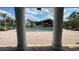 View of the pool from beneath stately white columns, surrounded by greenery and neighborhood buildings at 2856 Somerset Park Dr # 102, Tampa, FL 33613