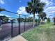 Exterior shot of a community tennis court, enclosed by a chain-link fence and surrounded by lush landscaping and palm trees at 2856 Somerset Park Dr # 102, Tampa, FL 33613