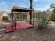 Backyard featuring a shaded pergola with red seating, and mature landscaping at 4325 Newbury Dr, New Port Richey, FL 34652