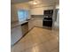 Well-lit kitchen with stainless steel appliances, granite counters, white cabinets, and tiled floors at 4325 Newbury Dr, New Port Richey, FL 34652