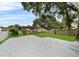 Large backyard with a concrete parking area, lush grass, and a mix of trees and shrubbery at 1906 E Ida St, Tampa, FL 33610