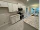 Modern kitchen with white cabinets, granite countertops, and stainless steel appliances at 6101 Roble Ave, Spring Hill, FL 34608