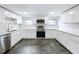 Renovated kitchen boasts white cabinets, stainless steel appliances, and dark tile floors at 8531 Bass Lake Dr, New Port Richey, FL 34654