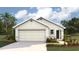 One-story home with light beige siding, two-car garage, and landscaping at 30900 Wild Juniper Ct, Brooksville, FL 34602