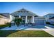 One-story home with gray siding, two-car garage, and landscaped front yard at 1280 Windy Bay Shl, Tarpon Springs, FL 34689