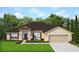 Traditional single-story home with a symmetrical facade, two-car garage, and manicured lawn at 13510 Canada Goose Rd, Brooksville, FL 34614