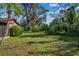 View of a grassy backyard with some overgrown vegetation beside the house at 1813 Laurel Oak Dr, Valrico, FL 33596