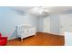 Well lit Bedroom with a white crib, ceiling fan, wood flooring, and neutral walls at 5808 Falconcreek Pl, Lithia, FL 33547