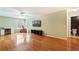 Spacious living room with hardwood floors, fan, television, and windows providing an abundance of natural light at 5808 Falconcreek Pl, Lithia, FL 33547