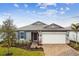 Curb appeal abounds in this charming new home; featuring a gray exterior, brick paver driveway, and lush landscaping at 5217 Patano Loop, Palmetto, FL 34221
