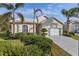 Tan one-story home with white garage door, landscaping, and palm trees at 750 Pond Lily Way, Venice, FL 34293