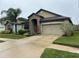 Tan house with stone accents, palm trees, and a two-car garage at 11854 Thicket Wood Dr, Riverview, FL 33579