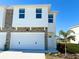 Two-story townhome with white exterior, stone accents, and a two-car garage at 13725 Emerald Fields Dr, Hudson, FL 34667