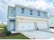 Two-story duplex with attached garages and light blue exterior at 13998 Emerald Fields Dr, Hudson, FL 34667