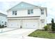 Two-story duplex with attached garages, light teal accents, and landscaping at 14016 Emerald Fields Dr, Hudson, FL 34667