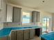 Kitchen with gray cabinets, gray herringbone backsplash, and island at 14016 Emerald Fields Dr, Hudson, FL 34667