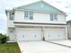 Two-story duplex with light blue accents, two-car garage, and driveway at 14024 Emerald Fields Dr, Hudson, FL 34667