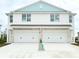 Two-story duplex with light blue accents, two-car garage, and driveway at 14024 Emerald Fields Dr, Hudson, FL 34667