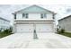 Two-story duplex with light blue accents, two-car garage, and driveway at 14024 Emerald Fields Dr, Hudson, FL 34667