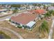 Aerial view of single-story home with tile roof, screened lanai, and lush landscaping at 1718 S Pebble Beach Blvd, Sun City Center, FL 33573