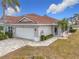 Villa features tile roof, two-car garage, and a paver driveway at 1718 S Pebble Beach Blvd, Sun City Center, FL 33573