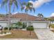 Villa with tile roof, two-car garage, and landscaped yard at 1718 S Pebble Beach Blvd, Sun City Center, FL 33573