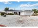 White single story home with a gravel yard, attached garage, and a small deck at 6628 Keystone Dr, Sarasota, FL 34231